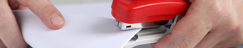 Staplers, hole punches, and everyday desk essentials arranged on a classroom desk
